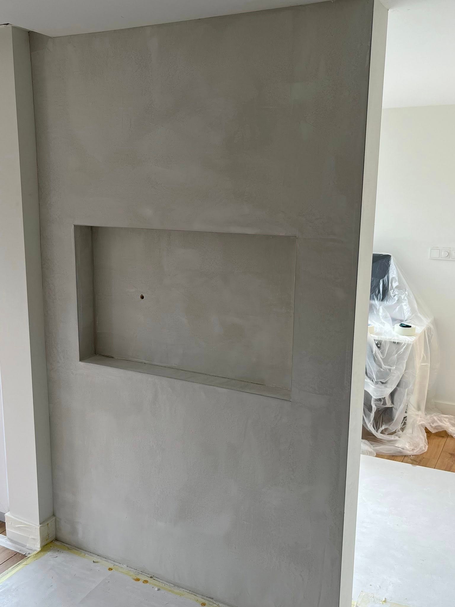 Strak gestucte grijze wand met een nis